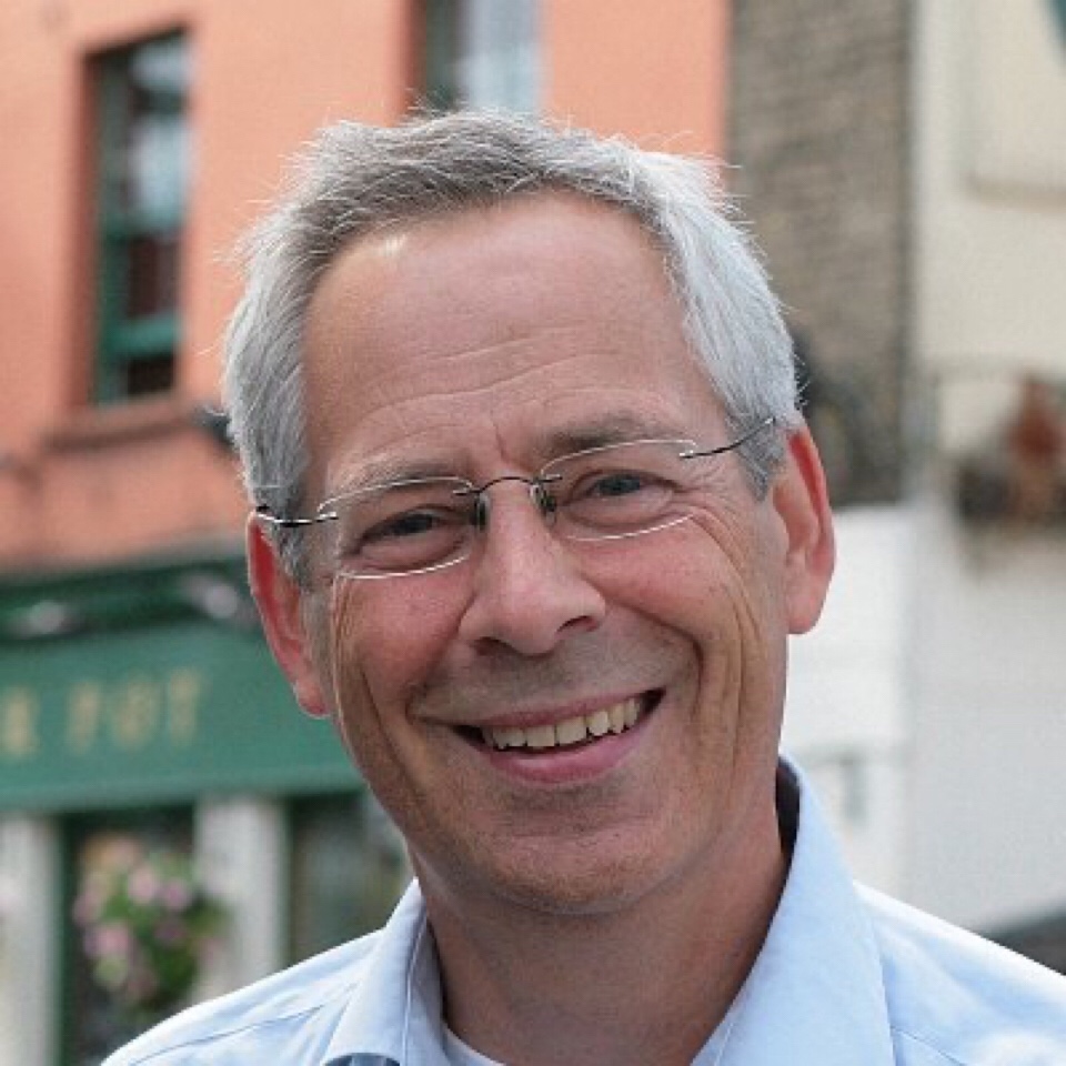 Headshot of Tim Gill, a smiling middle-aged white man wearing glasses.