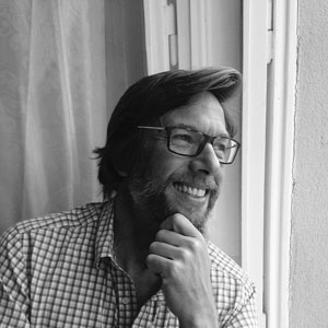 A black and white headshot of Bruce Appleyard, a white man with beard and glasses